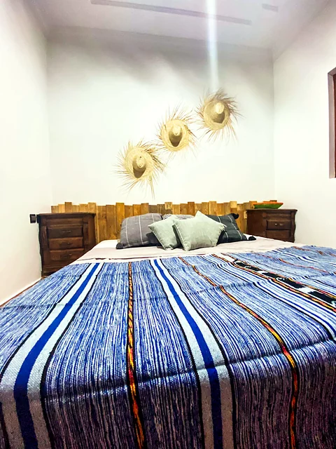 King room with wooden headboard, straw hats and blue Moroccan blanket